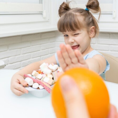 kilkuletnie dziecko wybiera słodycze zamiast owocu