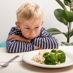 smutny chłopiec nad talerzem brokułów